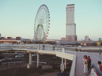 People at amusement park against clear sky