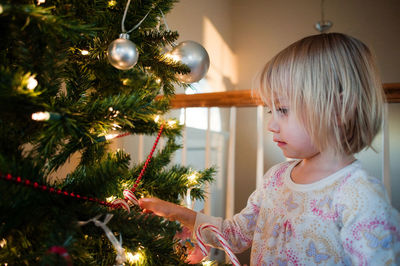 Girl touching christmas tree at home