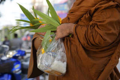 Midsection of monk holding religious offering