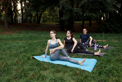 The relaxed girls is doing yoga in the park on carpet