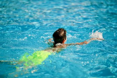 Rear view of man swimming in pool