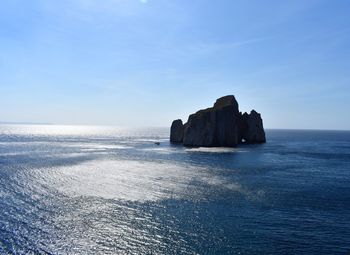 Rock formation in sea against blue sky