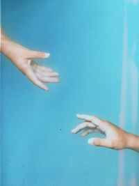 Midsection of woman hand against blue wall