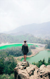 Rear view of man looking at mountains against sky