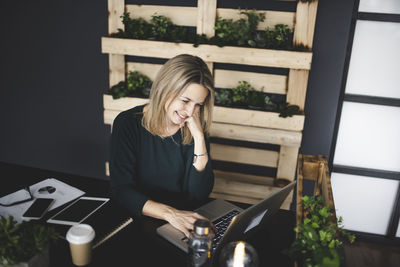 Young woman using phone while sitting on table