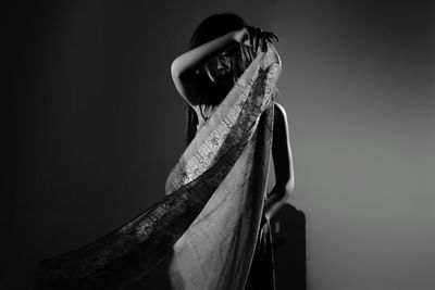 Close-up of woman holding hat against black background