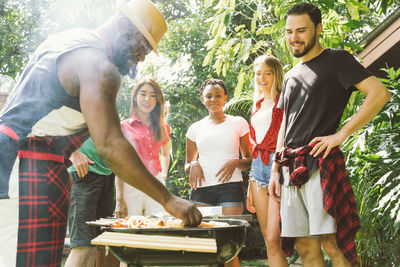 Man with friends preparing food on barbecue grill