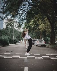 Full length of woman on road against trees in city