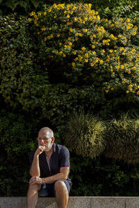 Man looking away while sitting in front of a vertical garden