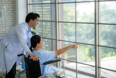 Side view of young man looking through window