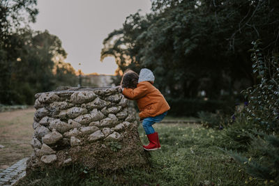 Side view of girl standing on rock in park