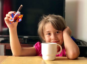 Portrait of girl holding protein bar at table