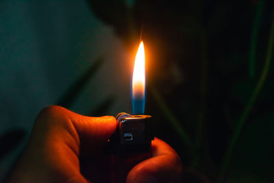 Close-up of hand holding burning candle