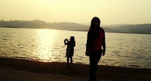 Silhouette of woman standing on lakeshore