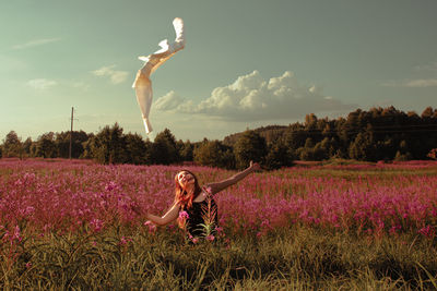 Full length of young woman with arms outstretched on grassy field