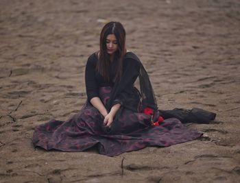 Portrait of young woman sitting on sand at beach