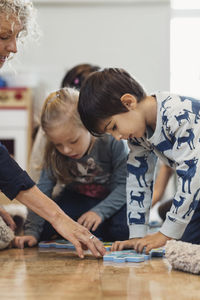 Teacher and children playing jigsaw puzzle