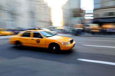 Blurred motion of yellow taxi on street in city