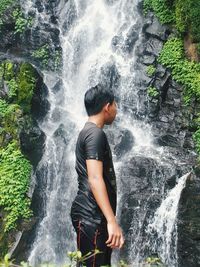 A young boy enjoys his vacation in a wonderful waterfall. the water is extremely fresh