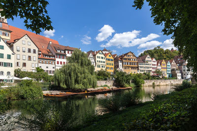 Buildings by river against sky