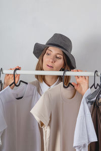 Woman millennial stylist chooses clothes on stylish railing in dressing room