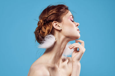 Young woman looking away against blue background