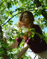 Low angle view of young woman against tree