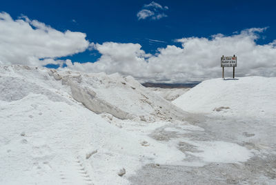 Information sign on salt flat against cloudy sky