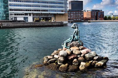 Stack of stones by river in city against sky