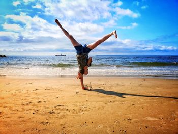 Full length of girl doing handstand on shore at beach