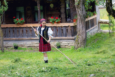 Full length of woman in traditional clothes cleaning yard