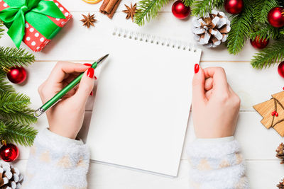 Top view of  hand writing in a notebook on christmas background. fir tree and decorations. new year.
