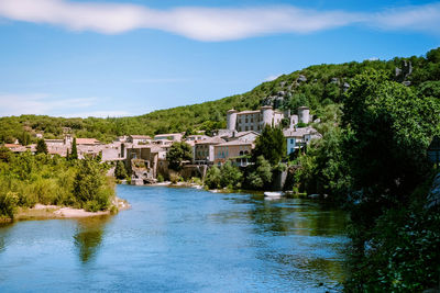 River amidst buildings and trees against sky