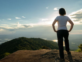 Rear view of man standing on mountain against sky