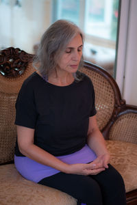 Senior woman with eyes closed sitting at home