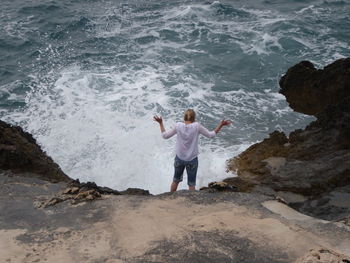 High angle view of man standing on rocks at beach