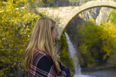 Rear view of woman standing against waterfall