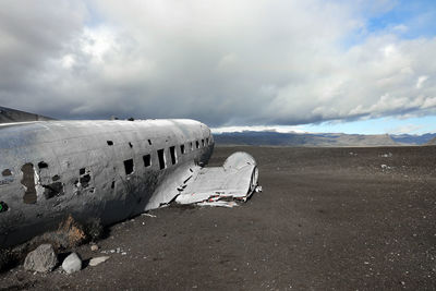 Damaged airplane on beach against sky