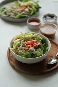 High  angle view of indonesian spicy salad, topped with peanut sauce on the table.