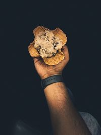 Close-up of man holding ice cream against black background