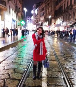 Full length portrait of woman standing on illuminated city at night