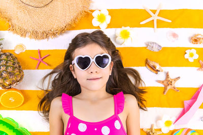 Portrait of young woman wearing sunglasses against wall