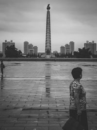 Rear view of woman standing against cloudy sky