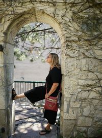 Side view of woman standing below arch