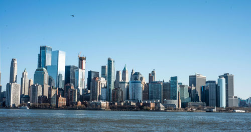 Sea by modern buildings against clear sky