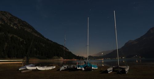 Sailboats moored on shore at beach against sky