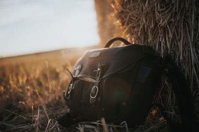 Close-up of bag by hay bale on field