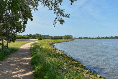 Footpath by river against sky