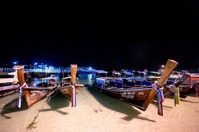 Boats moored on beach against sky at night