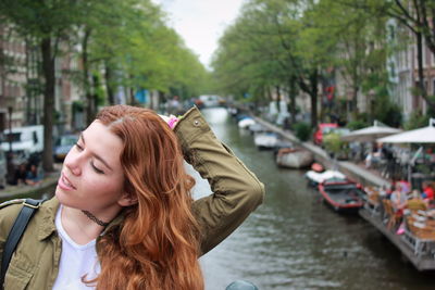 Close-up of young woman with redhead against canal in city